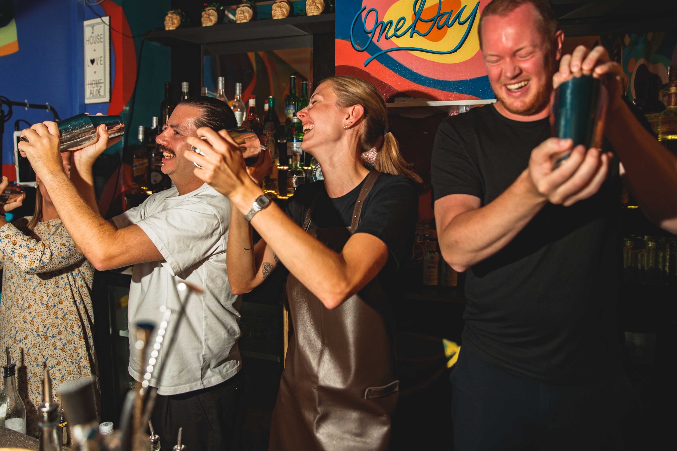 Fire personer deltager i et cocktailkursus og lærer at shake  cocktails med professionelle bartendere